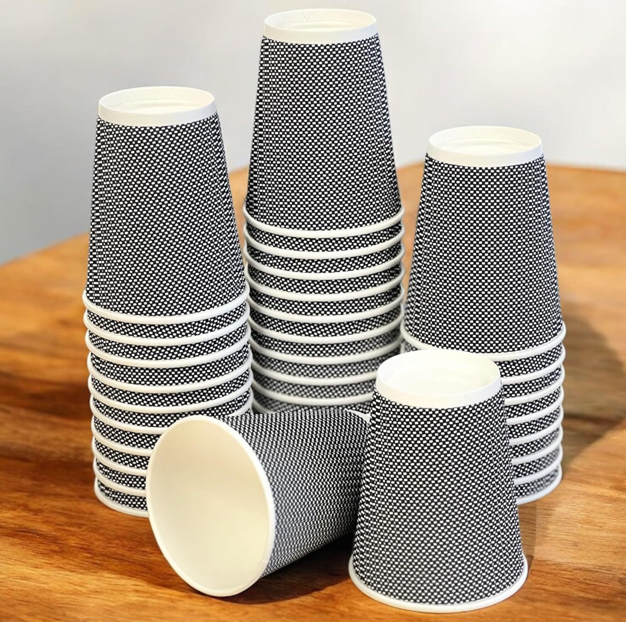 Stack of black and white patterned paper cups on a wooden surface