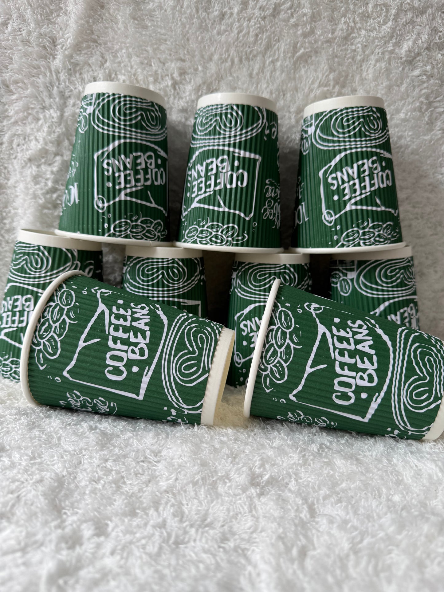 Green and white coffee-themed paper cups on a textured surface