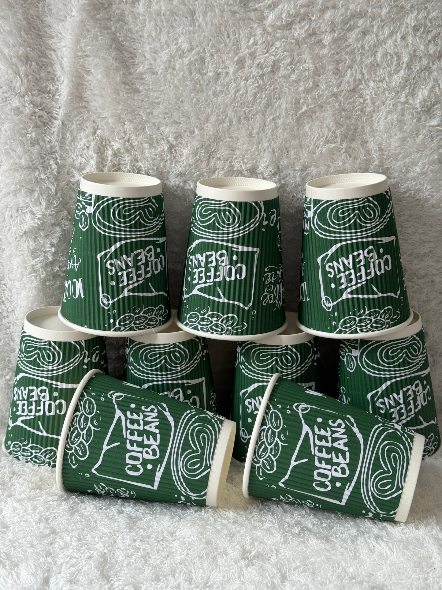 Green paper cups with 'Coffee Beans' text on a gray background