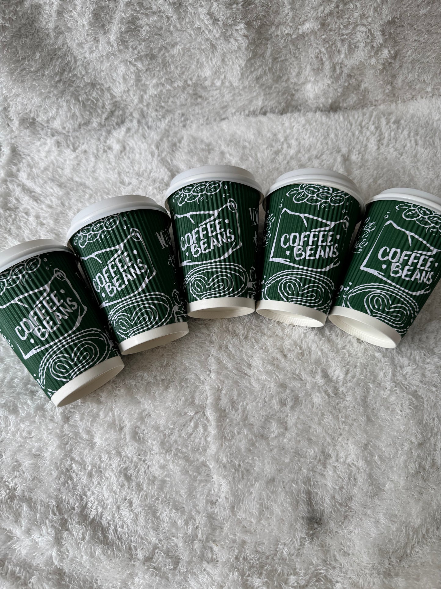 Row of green coffee cups with white text on a gray surface