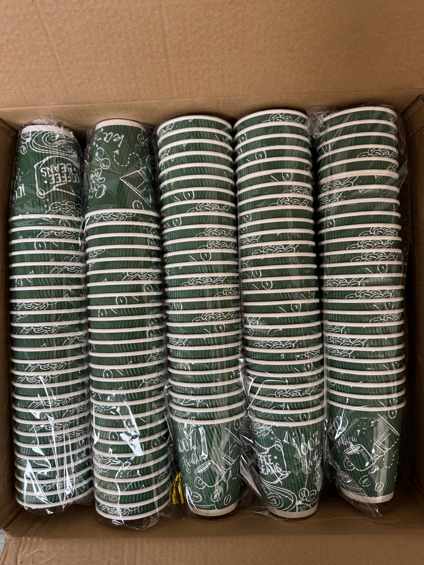 Five rolls of green fabric with white patterns in a cardboard box