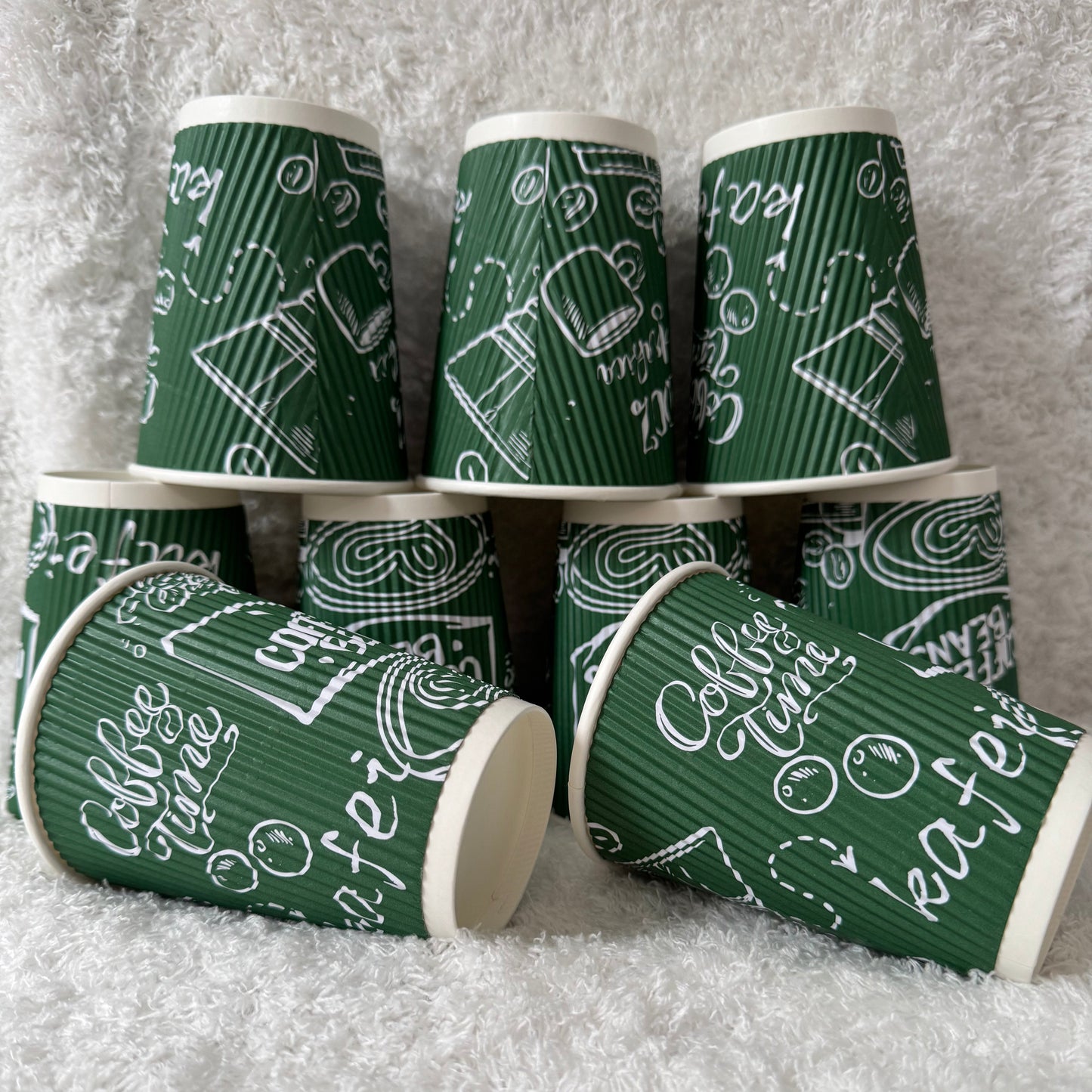 Stack of green paper cups with white text on a textured gray surface