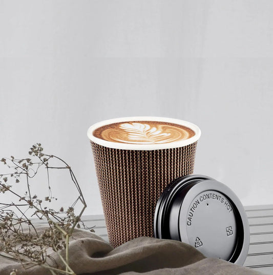 Cardboard coffee cup with a lid on a textured surface with a light gray background