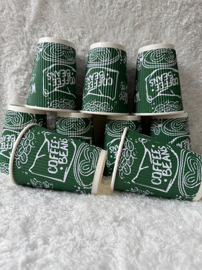 Green and white coffee-themed paper cups on a textured surface